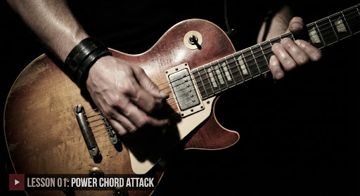 A guitarist striking the strings of a vintage electric guitar